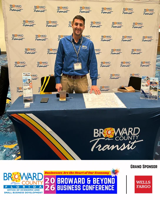 Smiling person standing behind Broward County Transit Table at the Broward & Beyond Business Conference.