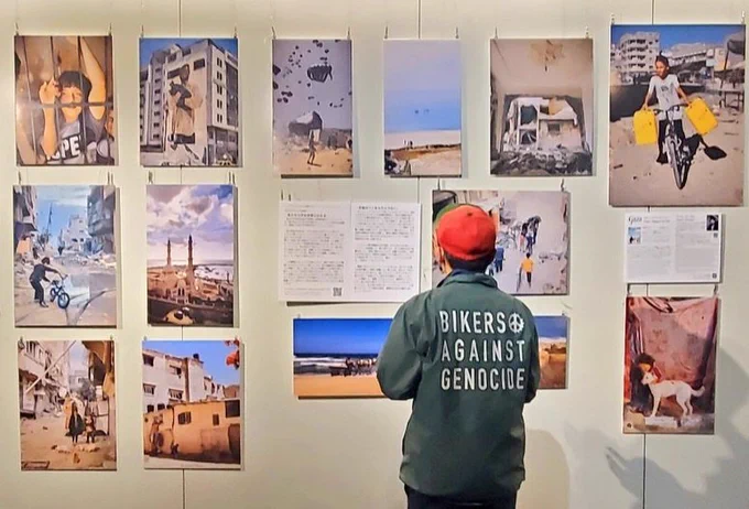 ガサの写真展に見入る男性
ジャケットの背中に
BIKERS AGAINST GENOCIDE
の文字