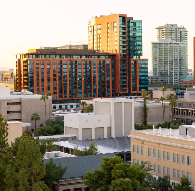 Modern high-rise buildings with glass and brick facades stand against a clear sky in Tempe Arizona downtown area.
