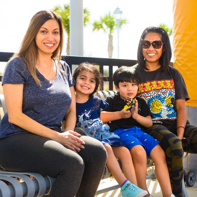 Mothers and children sit on a bench at a SunRail station.