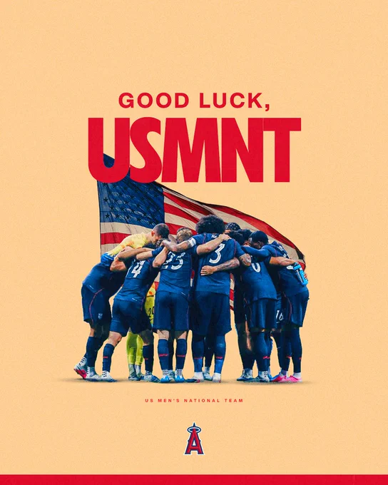 Good luck, USMNT (U.S. Men's National Team)! The team is pictured huddling together in their blue uniforms, with a large American Flag featured in the background. 