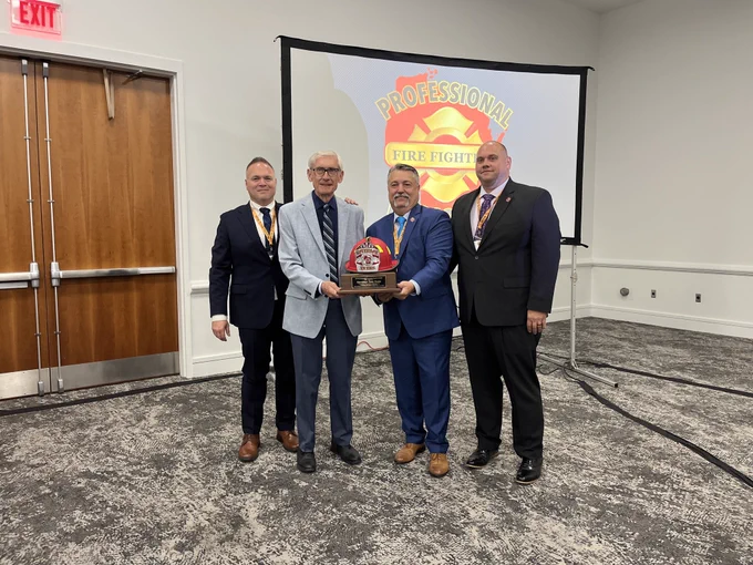 Gov. Evers holds award with PFFW leadership