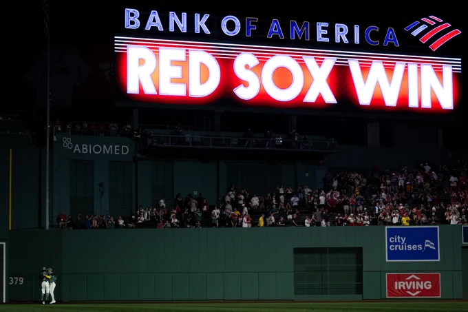 Jarren Duran, Ceddanne Rafaela and Wilyer Abreu celebrate in the outfield after the Red Sox win over the Texas Rangers at Fenway Park. The crowd is visible in the background along with the "Red Sox Win" graphic on the video board.