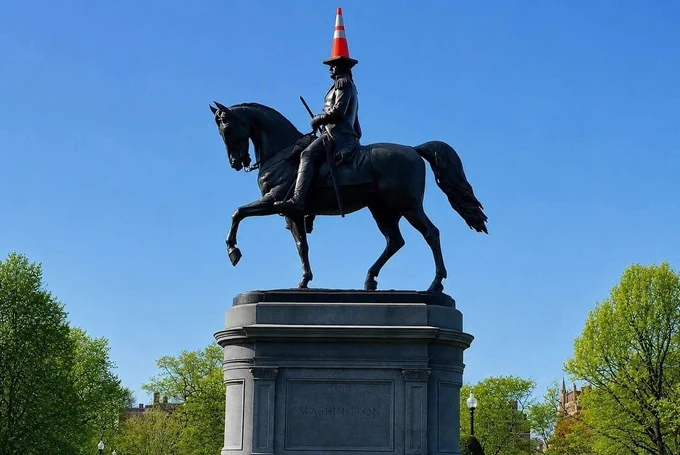 A statue of a mounted George Washington with a traffic come on his head.