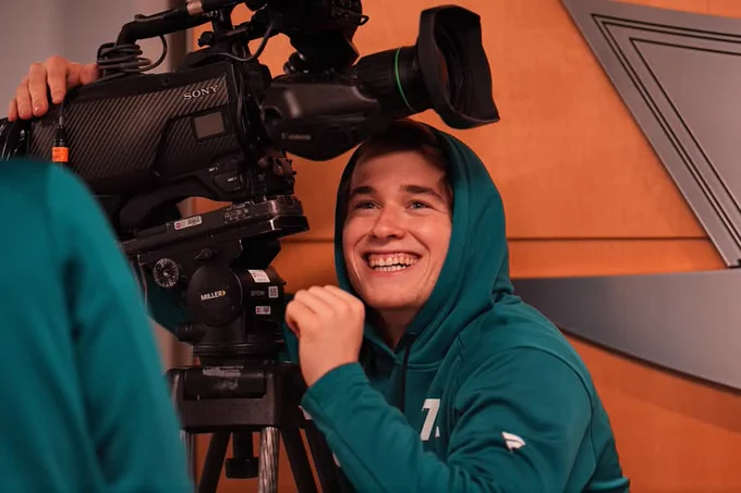 Macklin Celebrini smiling before a game as he plays with a camera