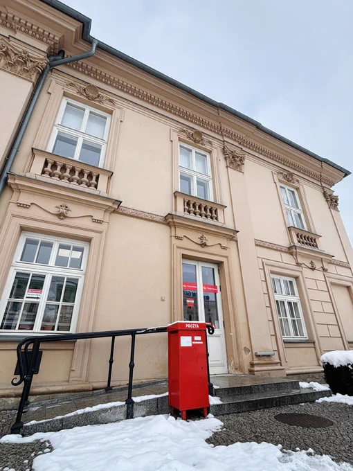 A red postbox outside a grand European building in the snow