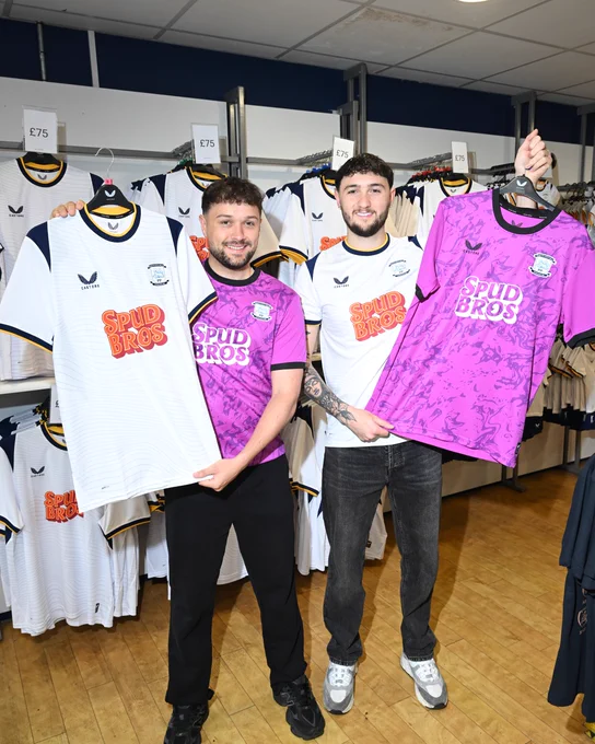 SpudBros wearing and holding up the new home shirt and home goalkeeper shirt.