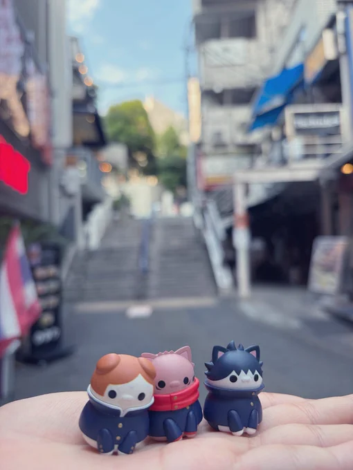 渋谷の街角を背景に猫としてデフォルメされた一年ズのフィギュアを撮った写真。背景はピンボケ