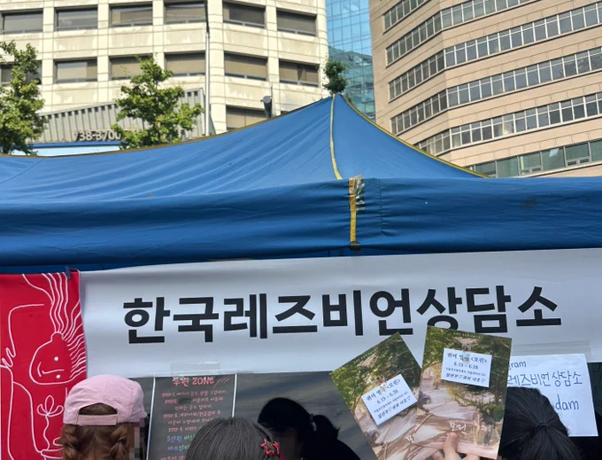 2026 서울퀴어퍼레이드 부스 중, 한국레즈비언상담소 부스 앞에서 영극 모린 포스터를 들고 촬영한 사진이다.