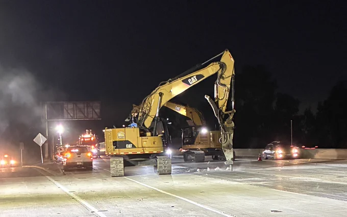 Excavator fitted with hydraulic hammer demolishing old concrete. 