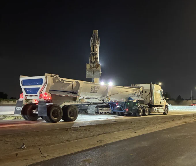 Excavator loading demolished concrete into dump truck. 