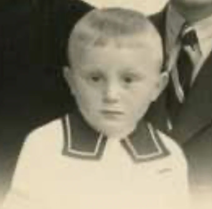 Black and white photo of a young boy in a sailor suit.
