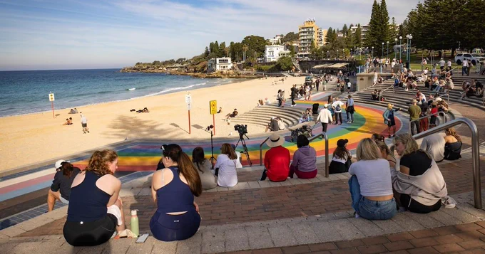 Woman mauled by shark off Sydney beach grabs onto a lifeguard's paddleboard