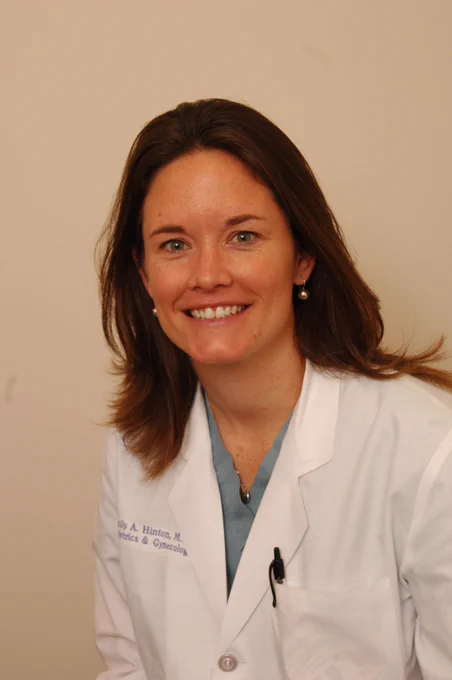 Dr. Emily Hinton in her white lab coat embroidered with her name and department.