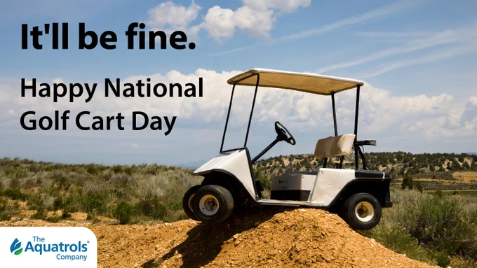 A golf cart is perched atop a small mound of dirt in a scenic outdoor landscape with shrubs and a distant horizon. Text on the image reads, "It'll be fine. Happy National Golf Cart Day." The Aquatrols Company logo is in the bottom left corner.
