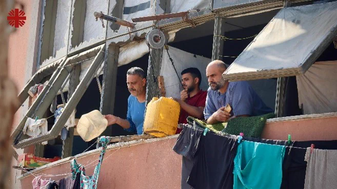 Men looking out of destroyed windows holding water containers. 