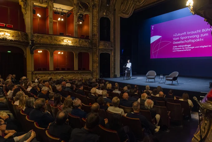Jutta Allmendinger spricht auf der BE-Bühne, davor Publikum im Saal