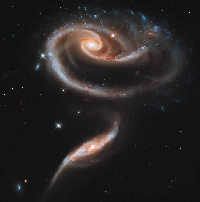 Hubble Telescope image of Arp 273: two spiral galaxies interacting to form the shape of a rose against a black, star-filled background.