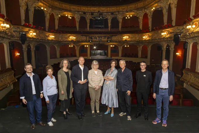 Gruppenfoto mit neun Personen auf der BE-Bühne mit Blick in den Saal