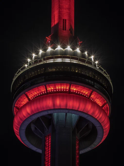 Closeup of the CN Tower at night lit red / Gros plan de la Tour CN illuminée en rouge la nuit 