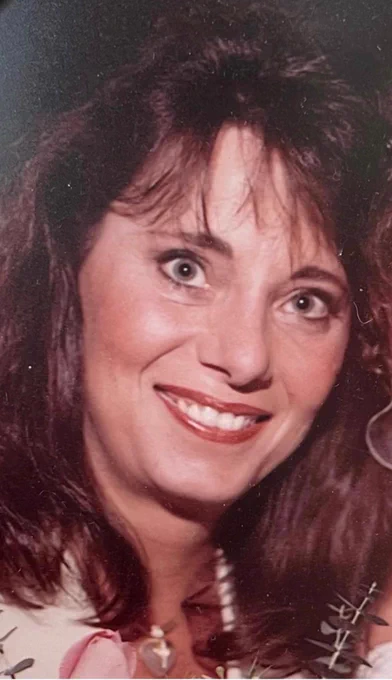 A close-up vintage photograph of a woman smiling widely, with vibrant makeup and a joyful expression. The image has a warm color tone, reminiscent of an old photograph.