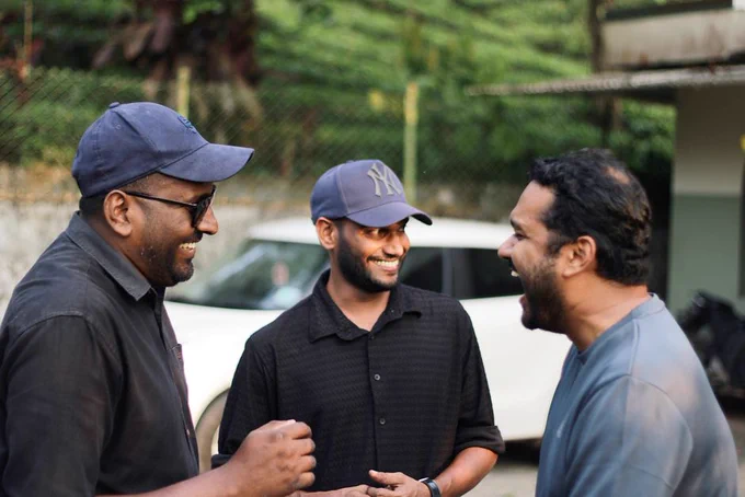 Three men enjoy a shared moment of laughter outdoors, capturing camaraderie in natural light.