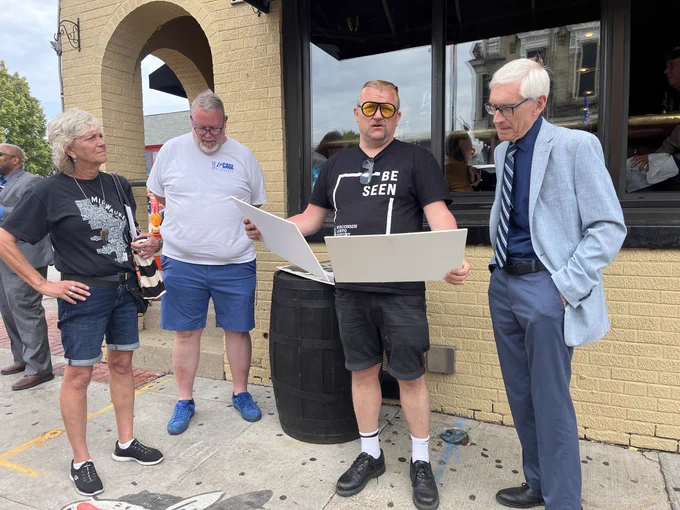 Gov. Evers looks at old photos during walking tour of neighborhood