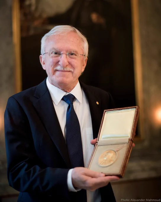 Paul Modrich looks at the camera while displaying his Nobel Prize medal.