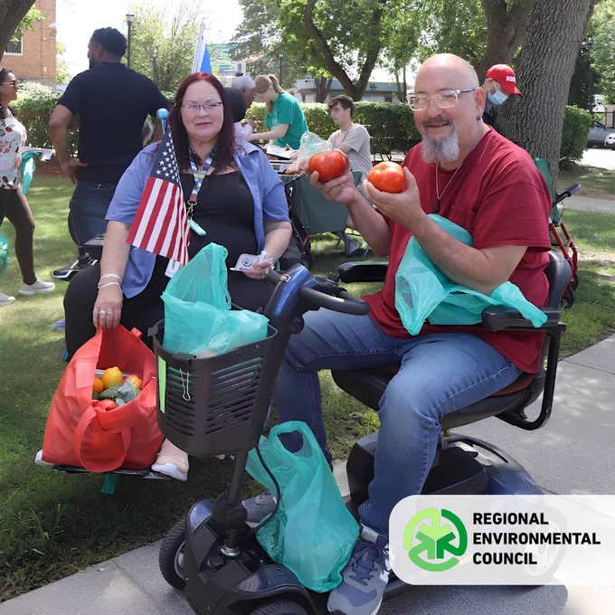 Two people on mobility scooters holding fresh produce at an REC Mobile Farmers market location. 