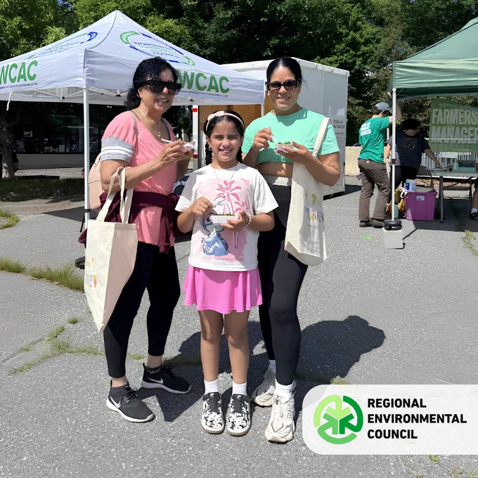 A family enjoying snacks at the REC Farmers Market at Beaver Brook park on a sunny day.