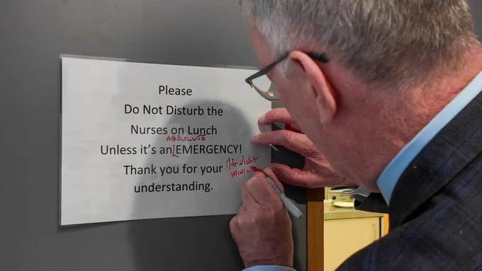 Health Minister Mike Nesbitt jokingly signs a notice at Omagh Hospital and Primary Care Complex requesting that nurses not be disturbed on their lunch break.