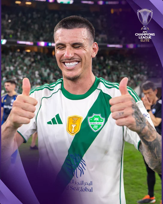 A soccer player is smiling and giving thumbs up with both hands on the field. The mood is celebratory and joyful, reflecting a success or victory in the AFC Champions League.