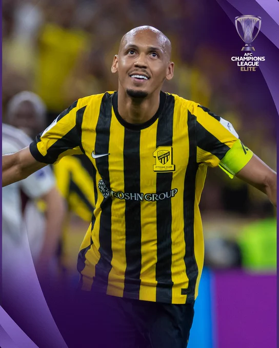 A football player from Ittihad Club in action, wearing a yellow and black striped jersey during the AFC Champions League.
