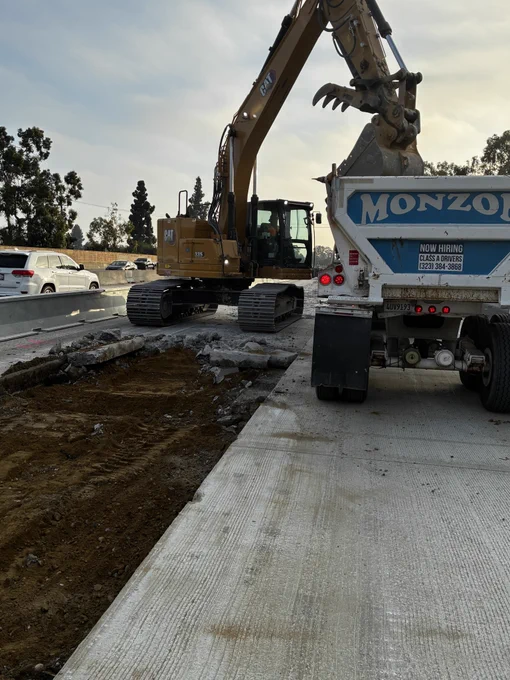 Excavator loading demolished concrete into dump truck. 