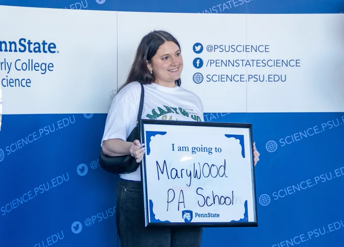 Girl posing with a whiteboard that reads "I am going to Marywood PA School."