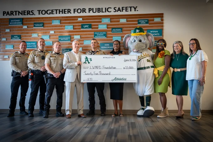 Group of officials and community members holding a $25,000 donation check from the Athletics to the LVMPD Foundation for public safety.