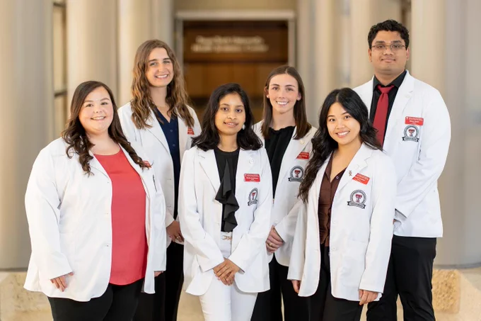 Six TTUHSC medical students stand together wearing white coats.