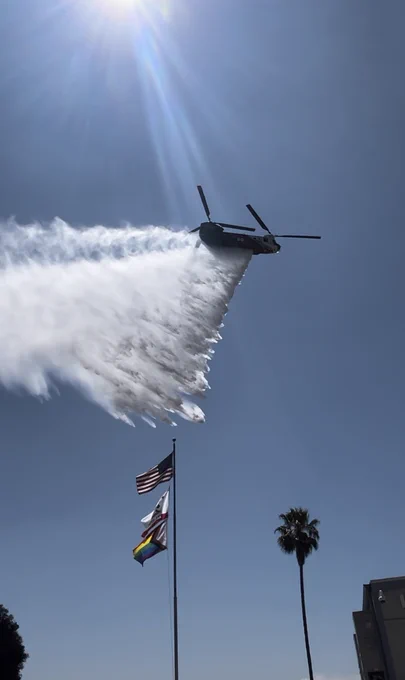 A helicopter flying overhead sprays water down.