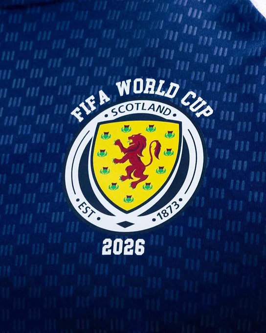 Scotland's FIFA World Cup 2026 crest on a dark blue patterned football shirt.