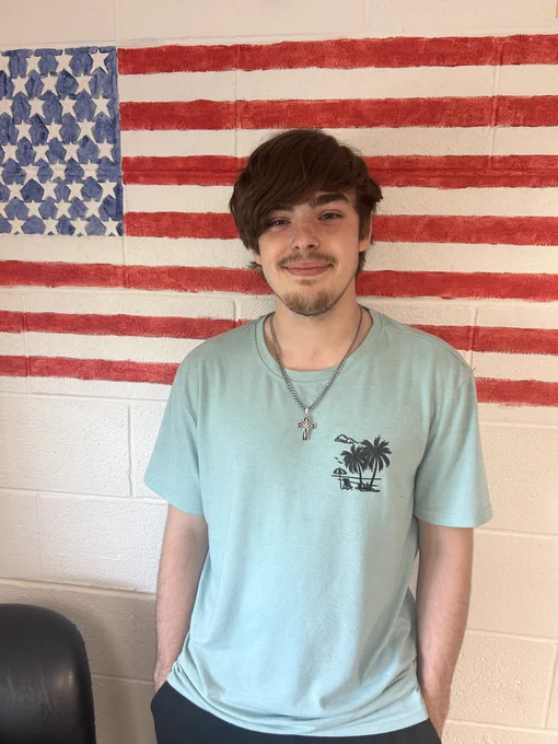 A student standing in front of an American flag.