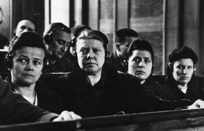 Historical black and white photo of several women attentively sitting in a courtroom.