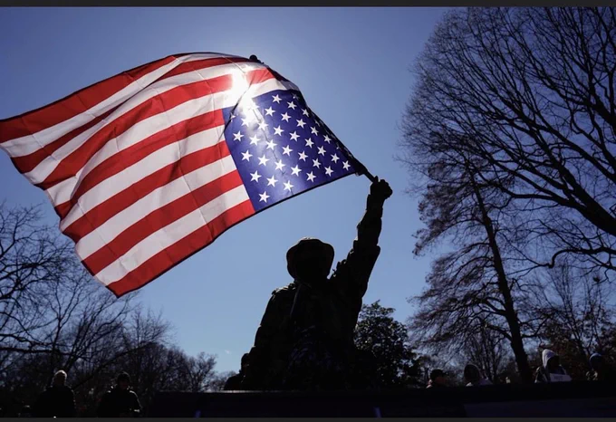 Upside down US flag being held high.