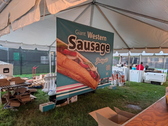 A sign that says Giant Western Sausage: Juicy's with a picture of the Giant Western Sausage covered in peppers and onions and whatnot 