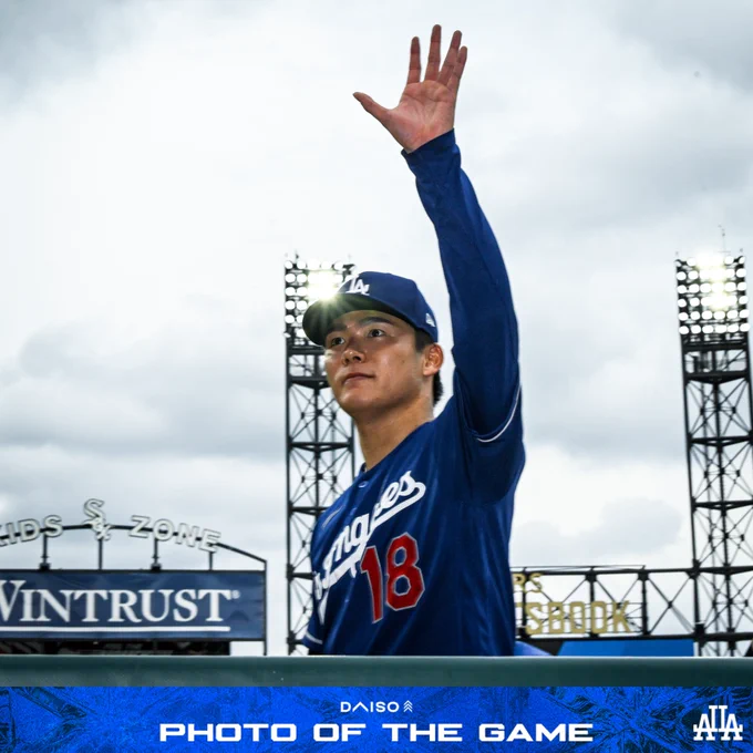 A photo of Yoshinobu Yamamoto waving to fans as he walks towards the dugout.