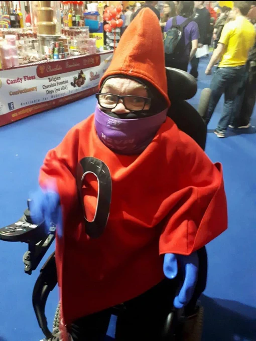 Me, a  powered wheelchair user, cosplaying as Master of the Universe's Orko