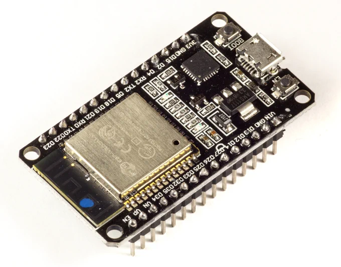 Close-up studio photo of a black ESP32 development board with header pins, a metal RF shield over the module, a micro-USB connector, and two pushbuttons on a white background.