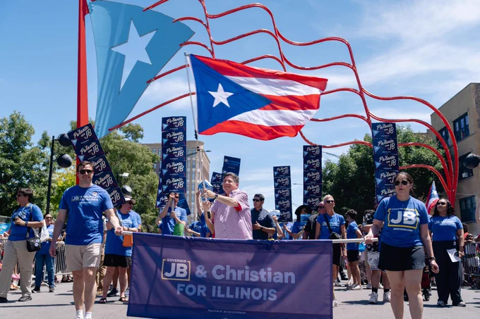Gov. Pritzker waves a Puerto Rican flag in the parade.