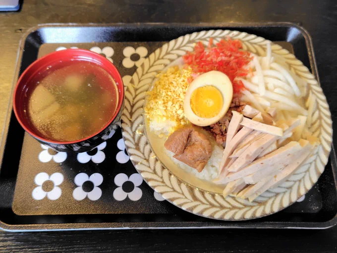 皿に平らに盛った塩味もち米の上に肉やハム、干しエビ、大根なます、卵などの具材がトッピングされている。