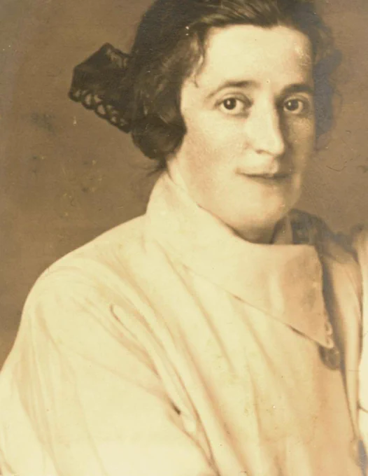 Vintage portrait of a woman wearing an elegant outfit with her hair styled up, looking directly at the viewer.
