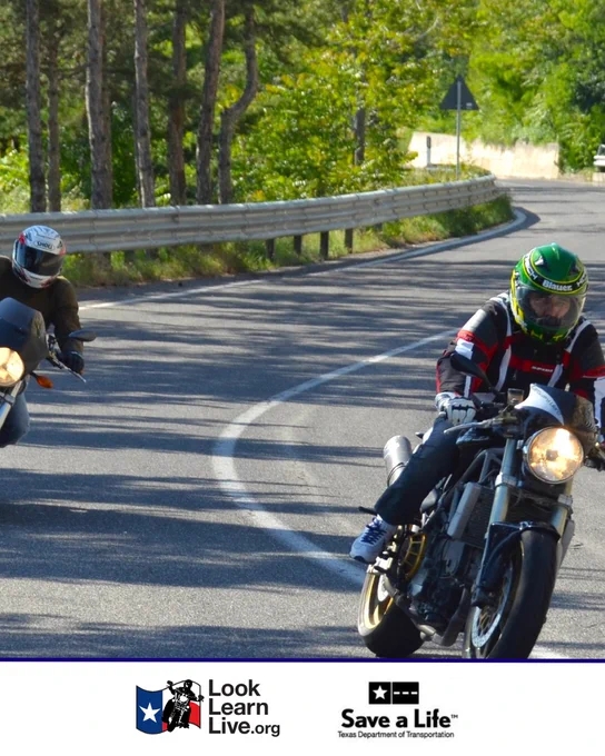 Motorcyclists navigate a winding road lined with trees. One wears a green and yellow helmet. A roadside barrier runs alongside the road. The bottom of the image displays logos for "Look Learn Live" and "Save a Life" Texas Department of Transportation.